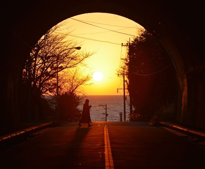 朝鮮海峡に沈む夕日でオレンジ色に染まるトンネル入り口＝5日午後5時50