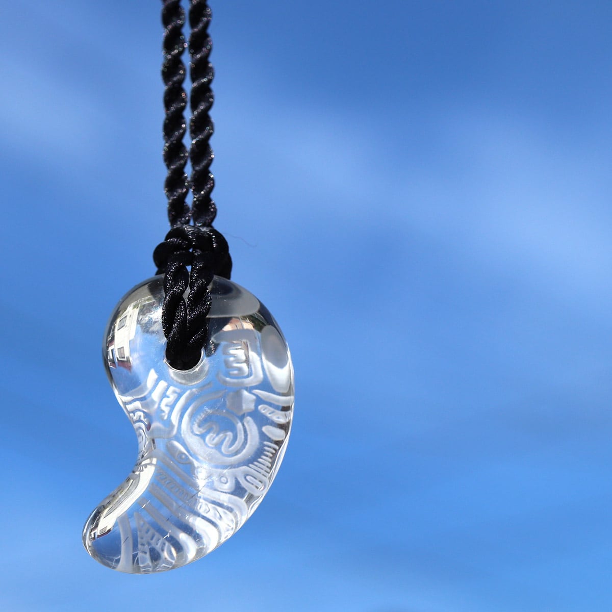 青空に映し出される縄文文様の勾玉水晶ペンダント（659-268