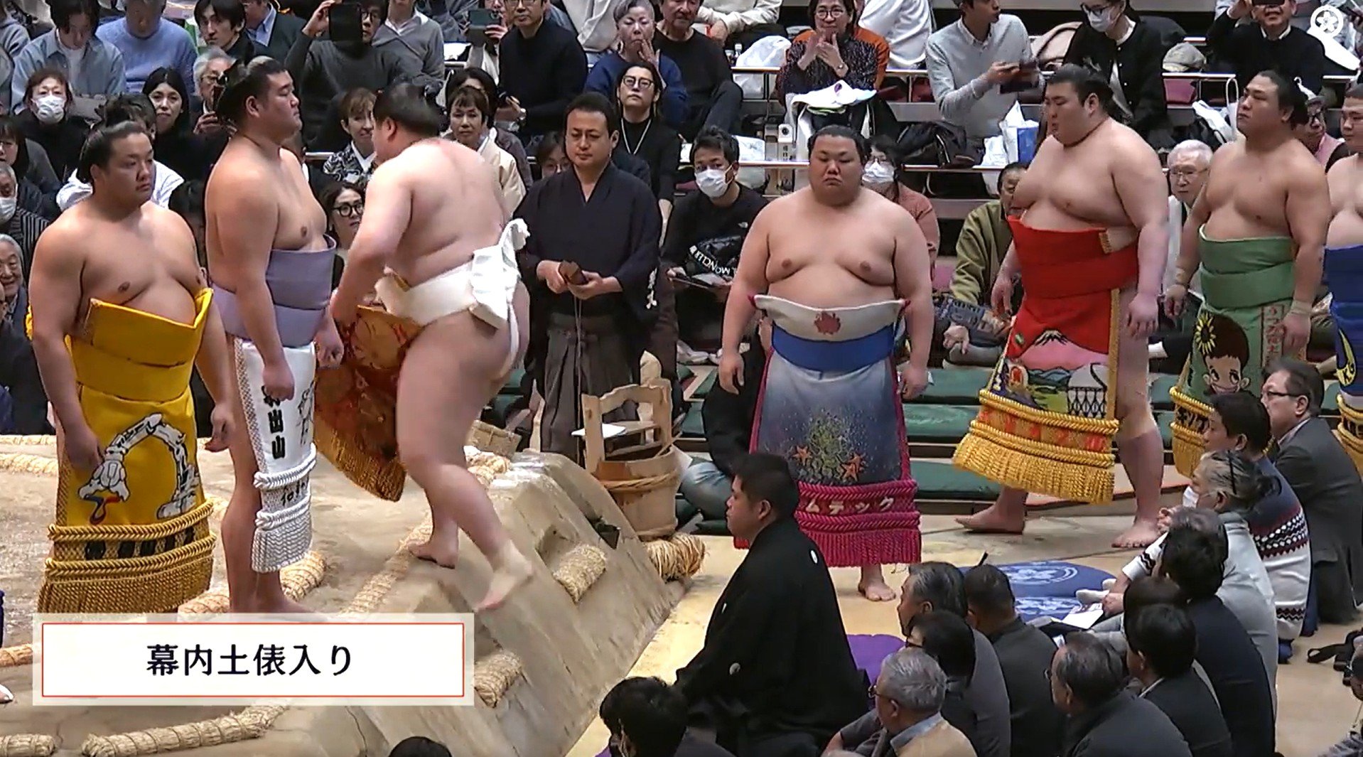 あれ、人気力士の化粧まわしに著名人のイラストが… 十両力士の腰には